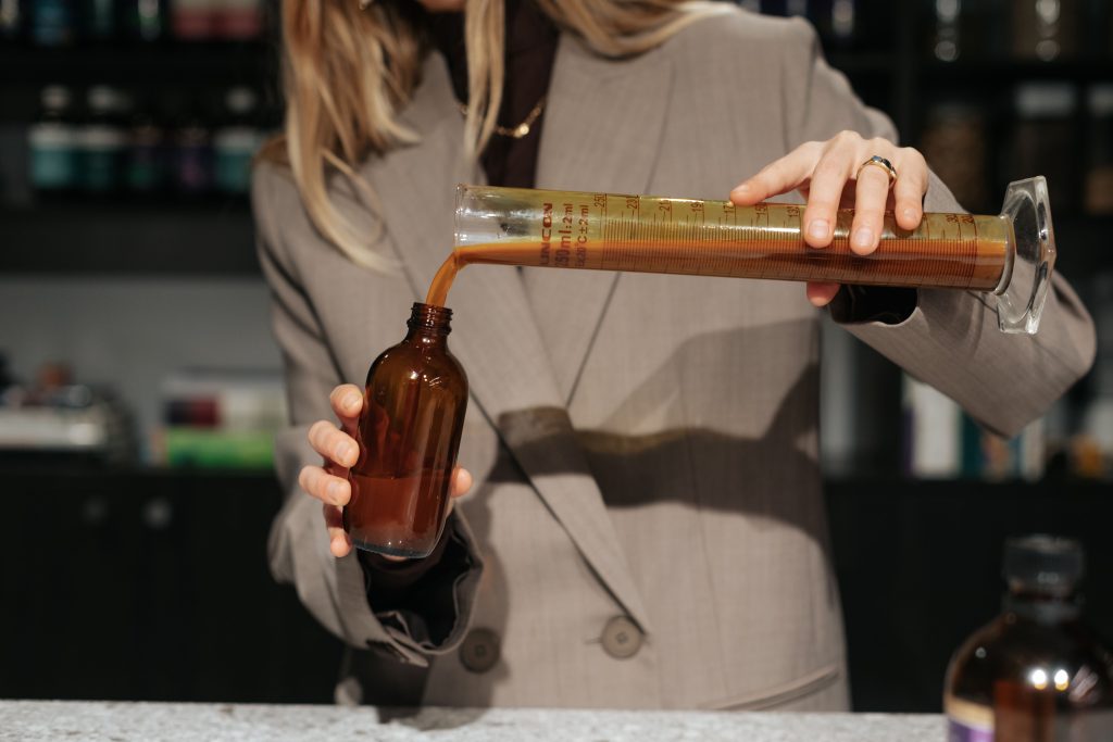 A close up of orange colored liquid being poured from a test tube into a bottle.