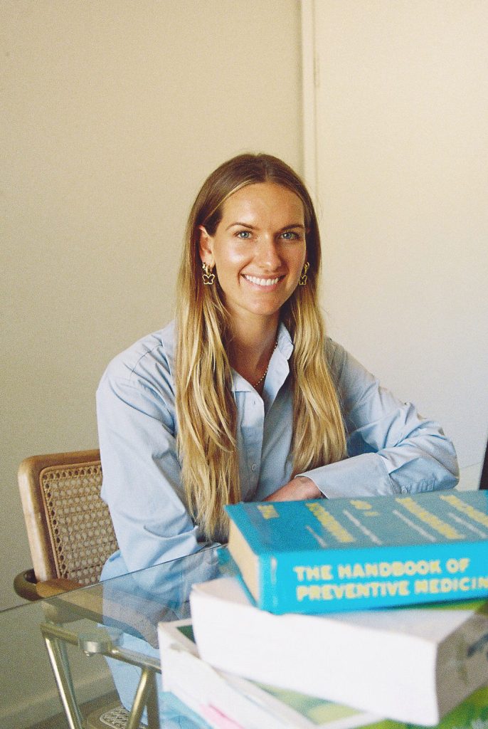 Elle-Lou sitting behind a desk with books on the table top.